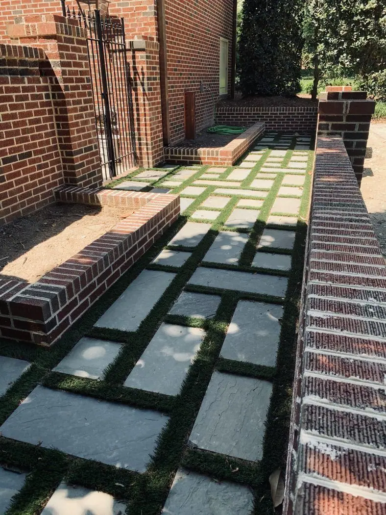 Brick bench walls beside bluestone stepping stones set in grass