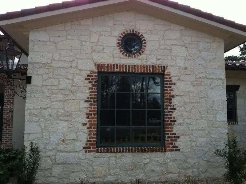Limestone wall with a brick window surround and a round brick oculus