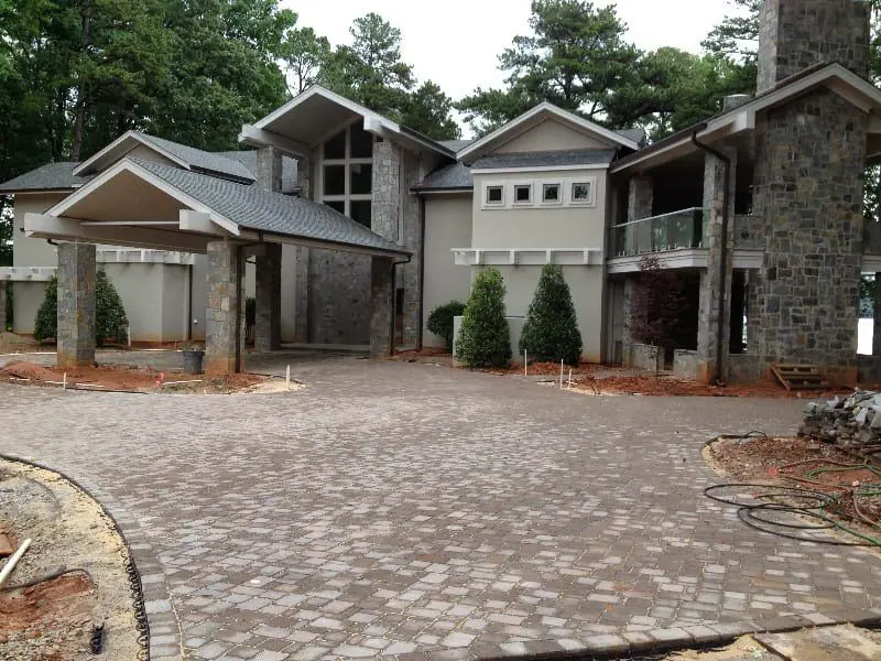 Tumbled paver motor court in front of a stone-and-shingle home
