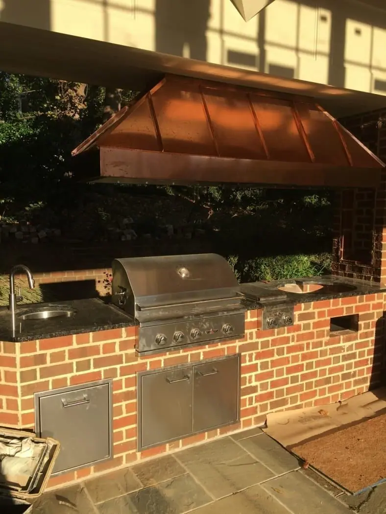 Brick outdoor kitchen under a copper vent hood