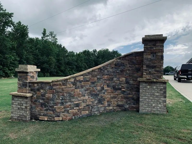 Curved stone veneer entry wall between brick-and-stone pillars