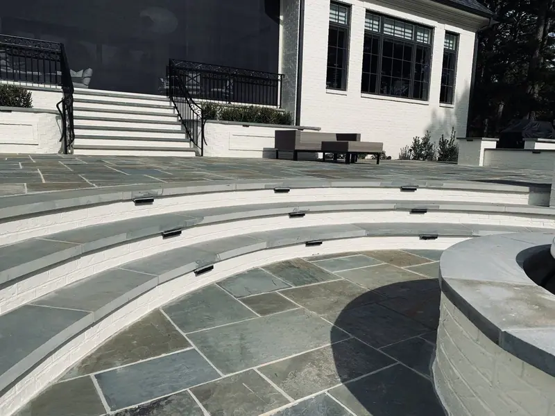 Curved bluestone steps and white brick walls rising to a house