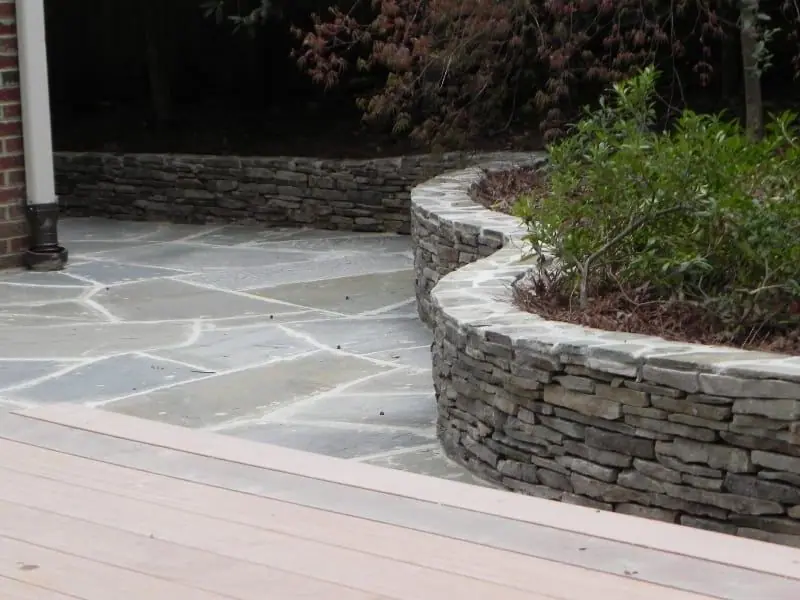 Curved dry-stacked stone seat wall beside a flagstone patio