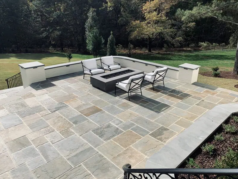 Flagstone patio with a fire table and capped white seat walls against the woods