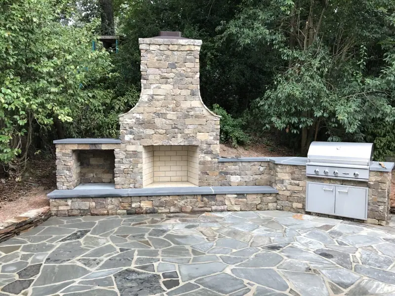 Stacked stone outdoor fireplace and grill counter on an irregular flagstone patio