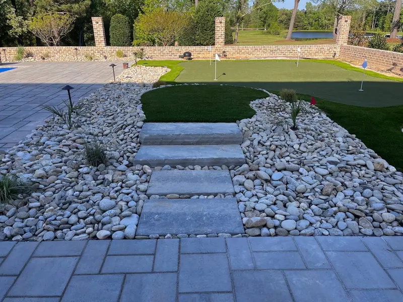 Paver stepping stones through river rock to an artificial putting green