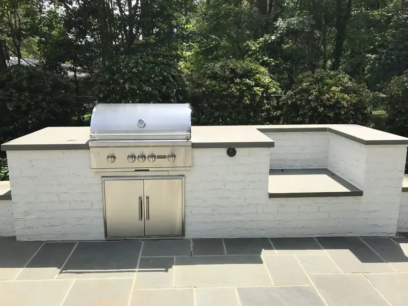 Whitewashed brick grill island with a stone countertop on a bluestone patio