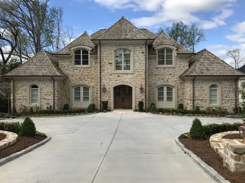 Natural stone facade with arched windows and cast-stone trim on a French-style home, built by Old South Masonry