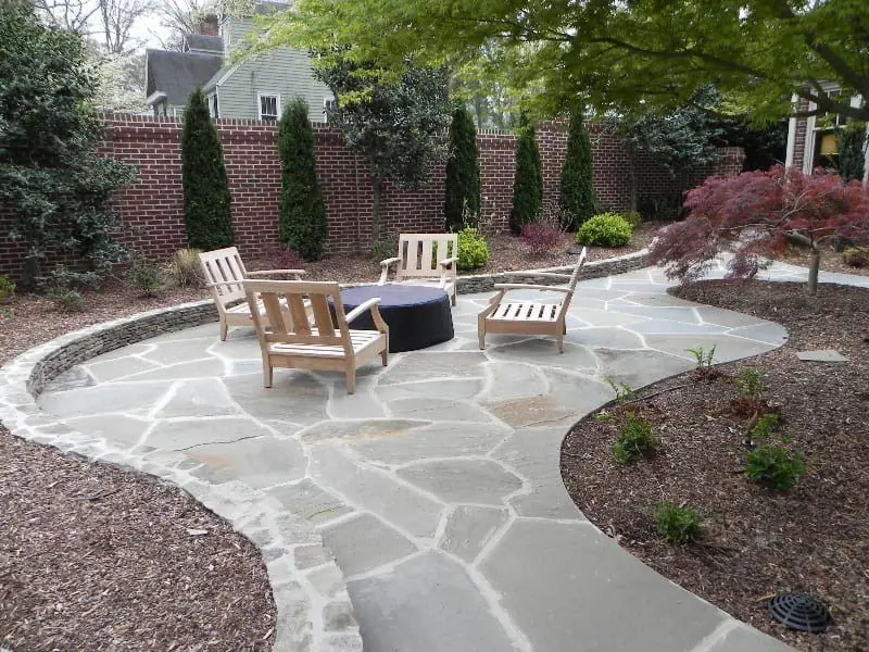 Curving flagstone patio and dry-stacked stone border around a Japanese maple