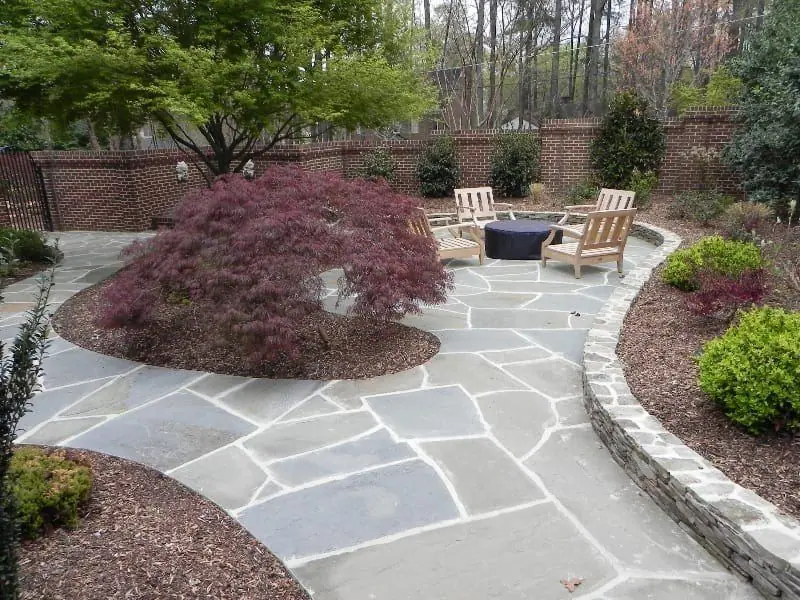 Flagstone path and dry-stacked stone edging winding past a Japanese maple
