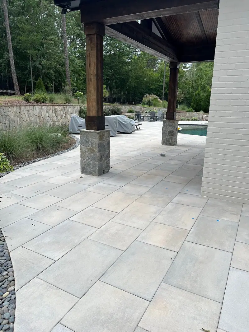 Large-format paver patio under a cedar pavilion with stone-clad posts