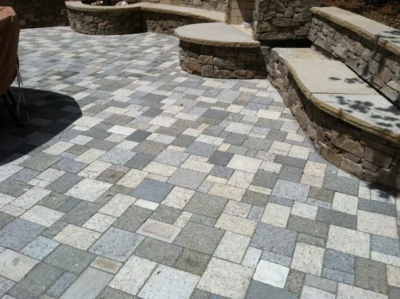 Tumbled paver patio rising into stacked stone seat walls with bluestone caps