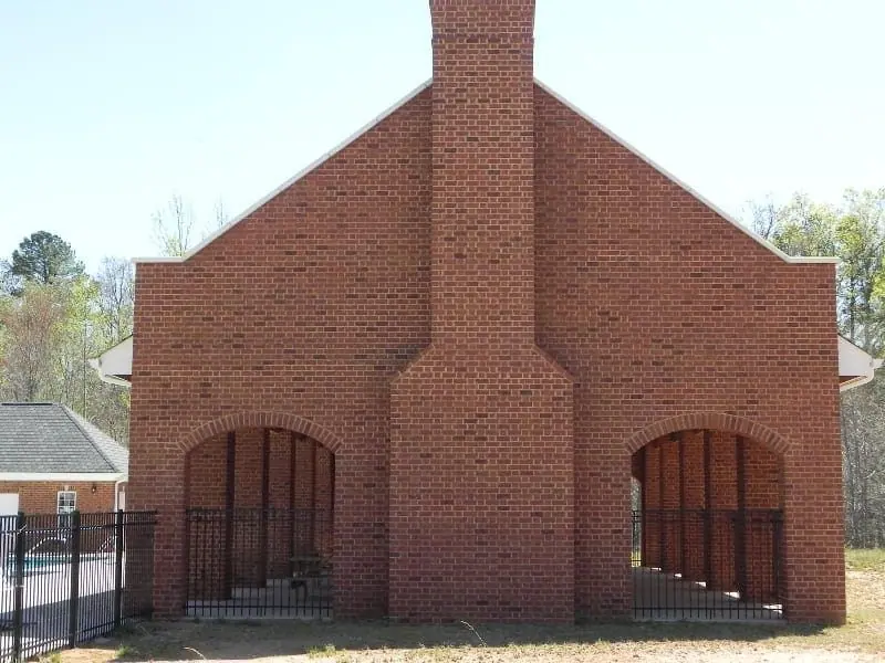 Brick pool pavilion with a central chimney and two arched openings