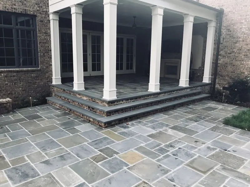 Bluestone porch floor and brick-edged steps under white columns