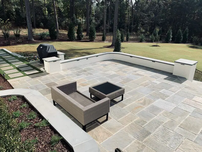 Bluestone patio with a capped seat wall and stepping stones running into the lawn