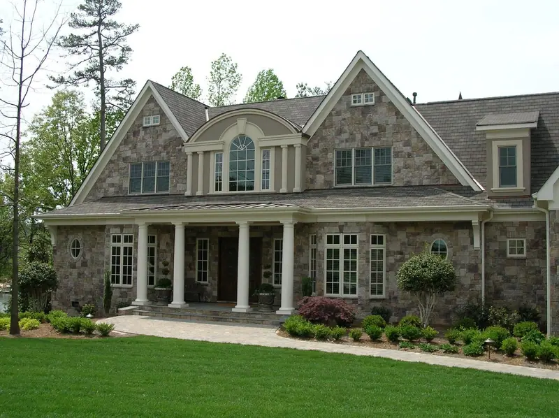 Two-story home with a natural stone veneer front, white columns and a paver walk