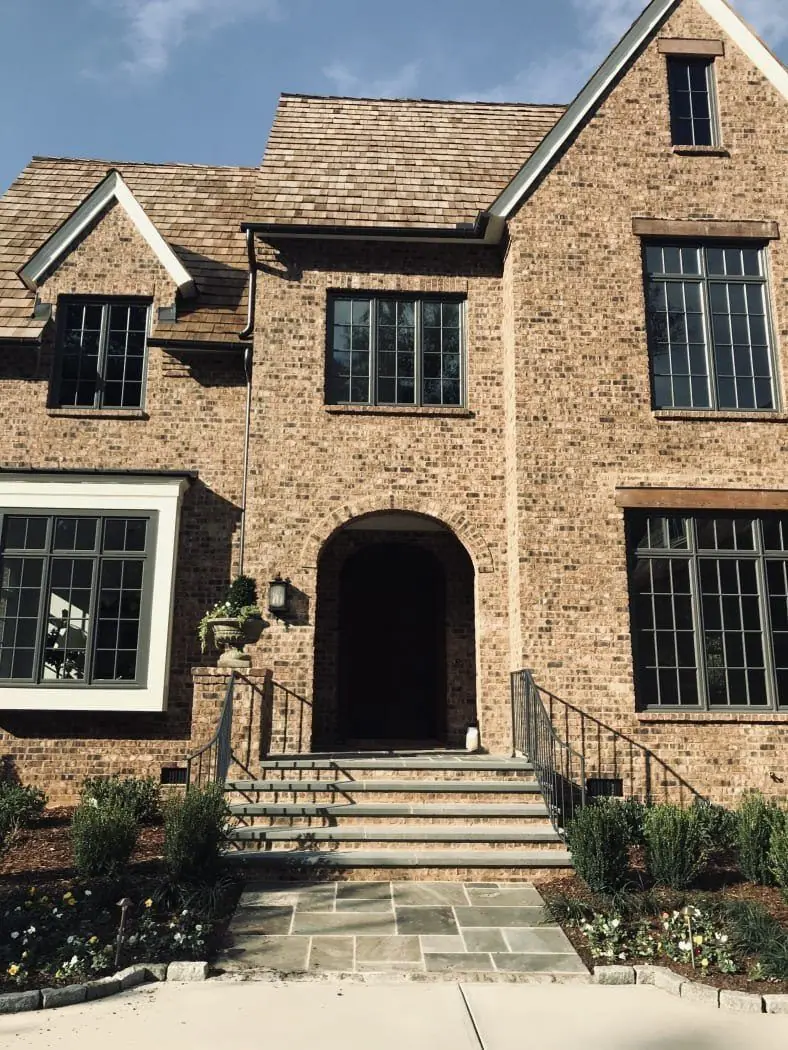 Brick Tudor-style home with an arched brick entry and stone front steps