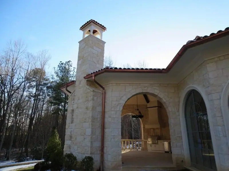 Limestone home with an arched loggia and a stone chimney