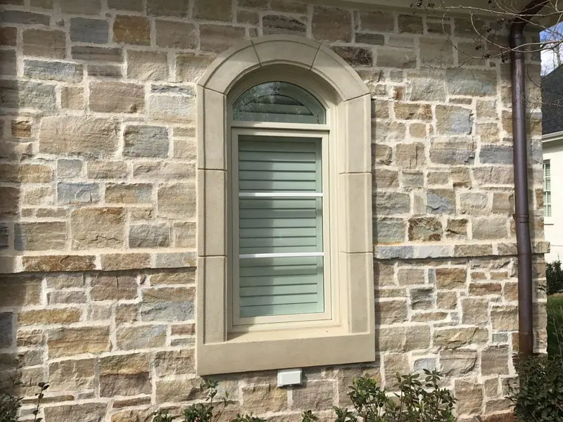 Natural stone wall with an arched cast-stone window surround